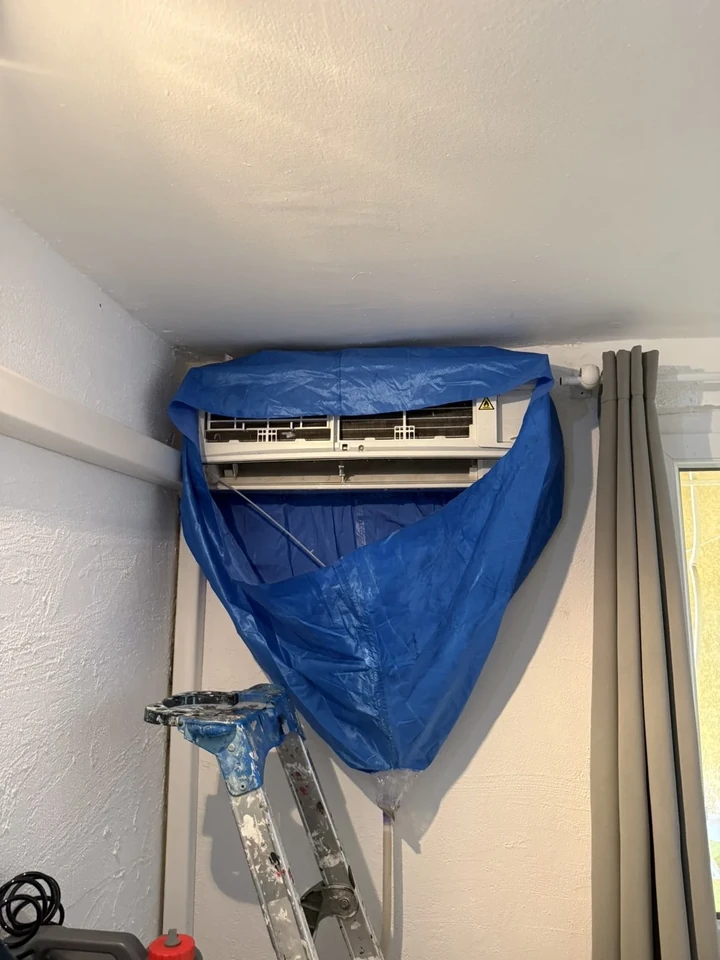 Nettoyage d’une unité intérieure avec une housse de protection bleue sur un chantier CL Climatech